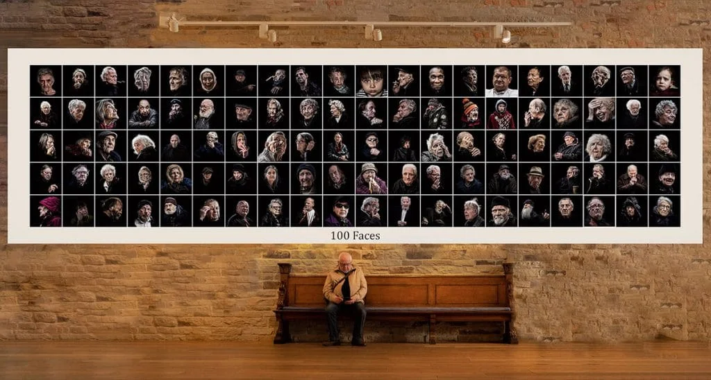 A woman sits on a bench in front of a large photo of people.