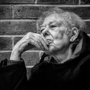 A black and white photo of an old woman with her hand on her chin.