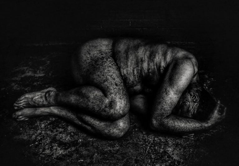 CT8 A black and white photo of a naked person laying on the ground.