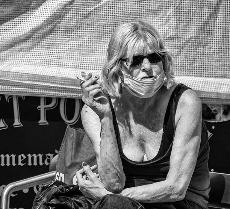 Photographs of the coronavirus lockdown-07 A woman sitting on a bench smoking a cigarette.