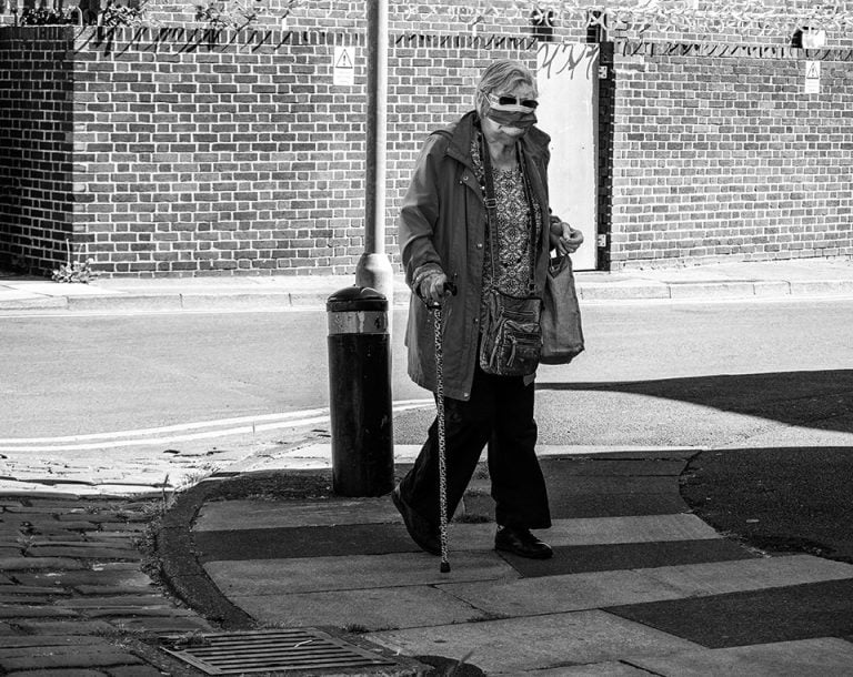 Photographs of the coronavirus lockdown-08 A woman walking down the street with a cane.
