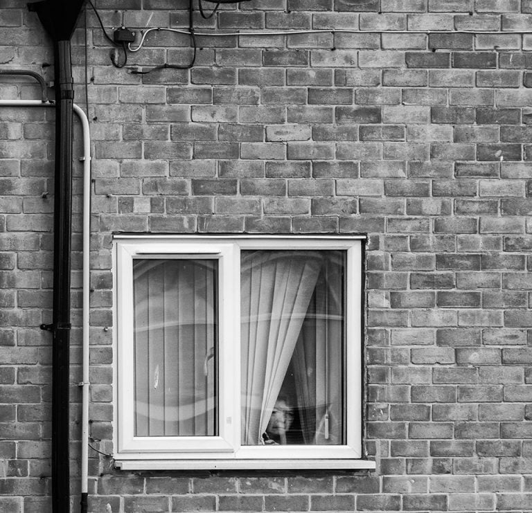 Photographs of the coronavirus lockdown-14 A black and white photograph of a window in a brick building.
