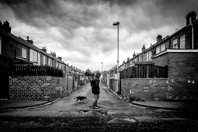Photographs of the coronavirus lockdown-15 A black and white photo of a person and a dog walking down a street.