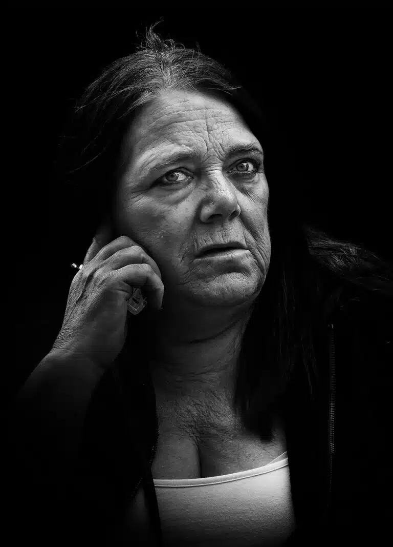 Faces_Photo_by John Gill-42 A black and white photo of a woman with her hand on her chin.