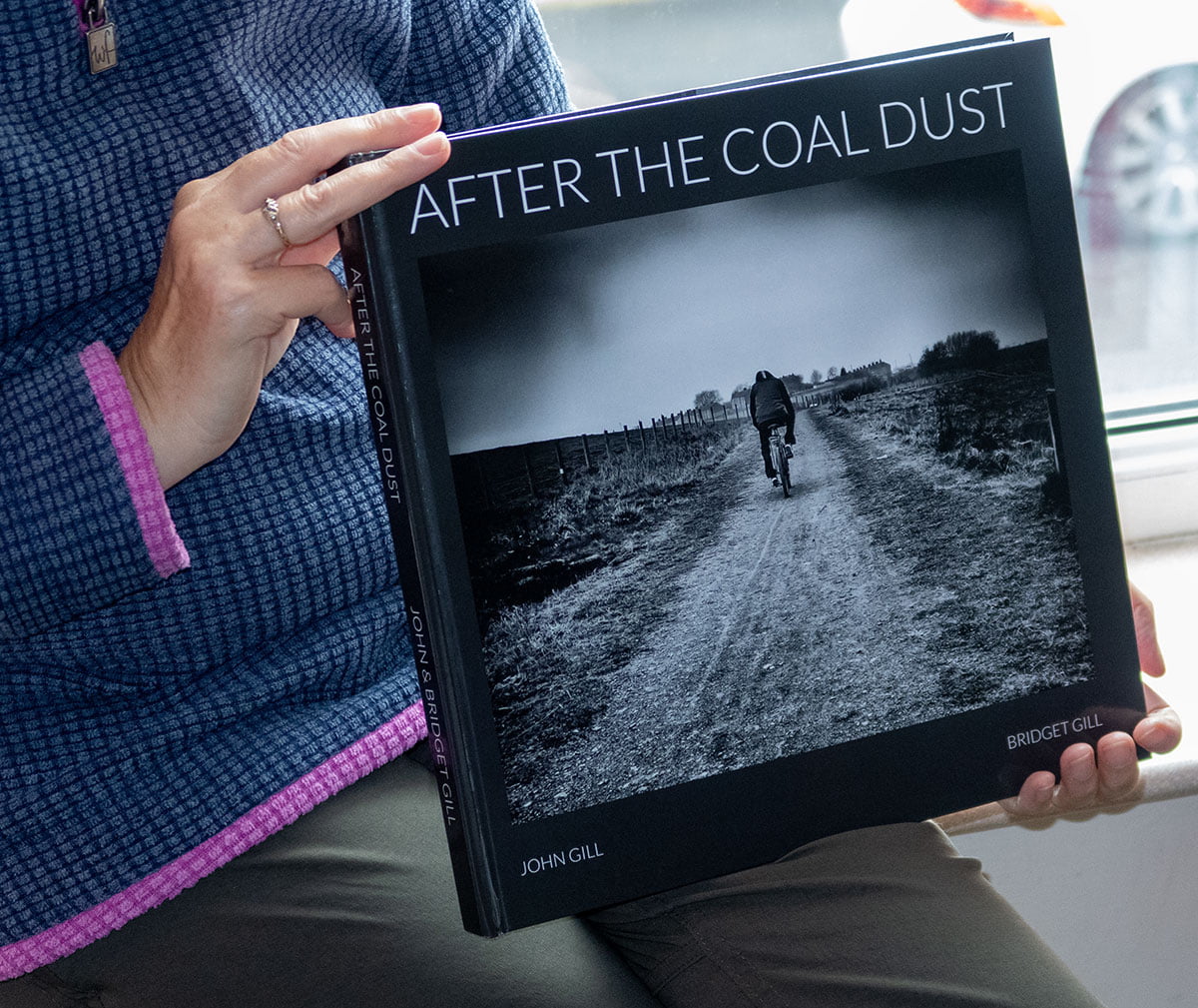 After the Coal Dust Book Review 19 A woman holding up a book with the title after the coal dust.