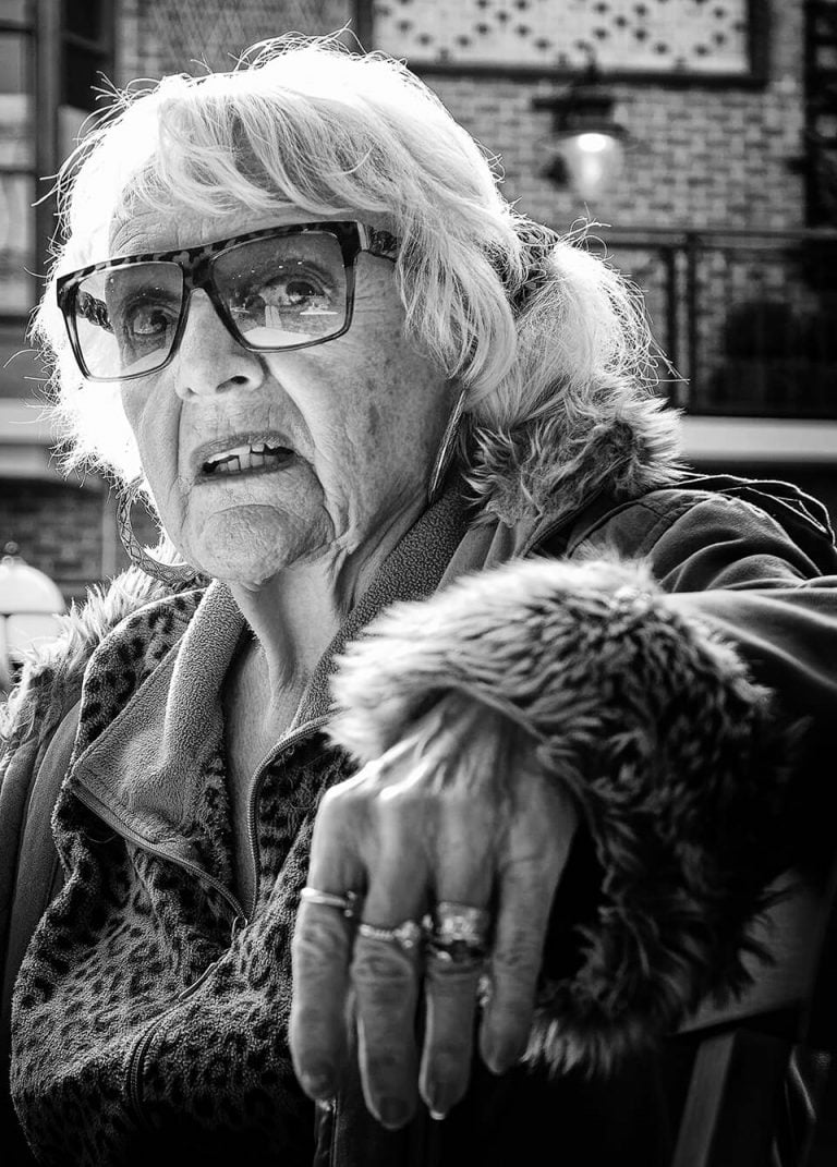 A black and white photo of an old woman wearing glasses.