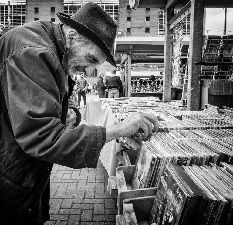 A man in a hat looking at records at a market.