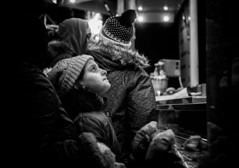 Black and white photo of a girl looking at a stall.