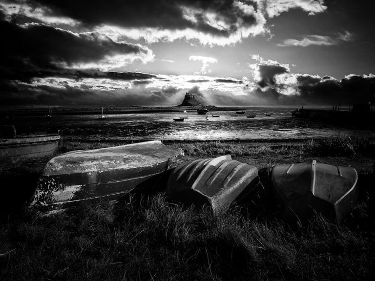 Black and white photo of old boats on a beach.
