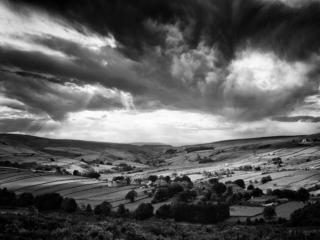 A black and white photo of a stormy sky over a valley.