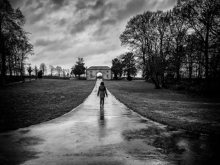 A black and white photo of a person walking down a path.