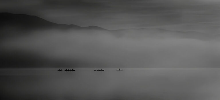 A black and white photo of a group of boats on a lake.