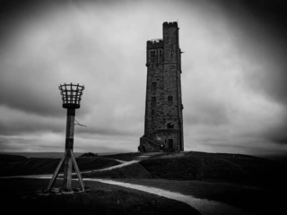 A black and white photo of a tower on a hill.