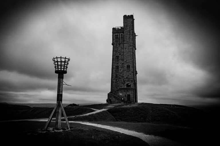 A black and white photo of a tower on a hill.
