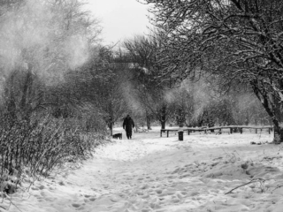 A black and white photo of a person walking in the snow.