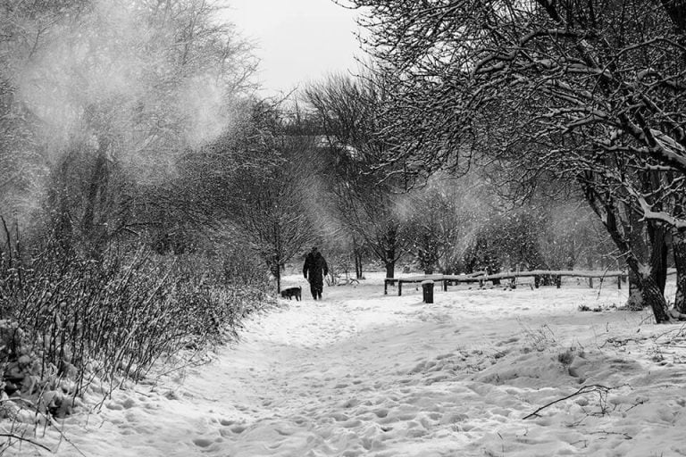 A black and white photo of a person walking in the snow.