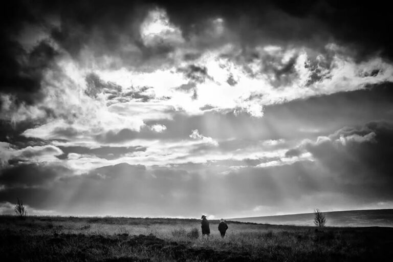 A black and white photo of two people standing in a field.