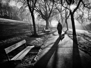 A black and white photo of a person walking down a path.
