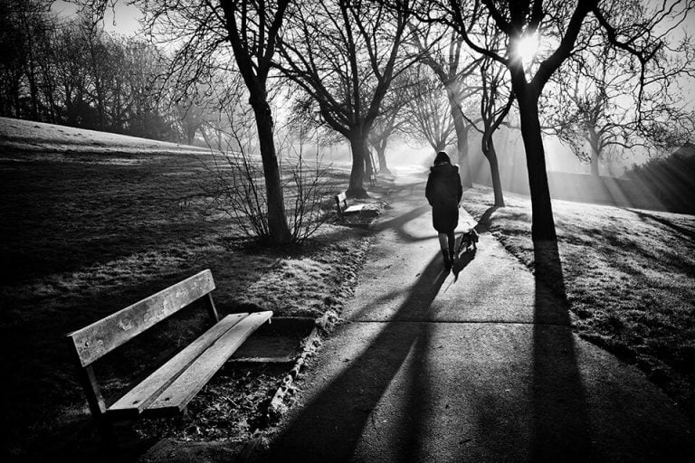 A black and white photo of a person walking down a path.