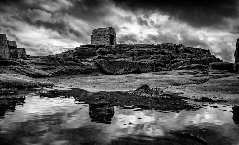 A black and white photo of ruins in the water.