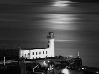 A black and white photo of a lighthouse at night.