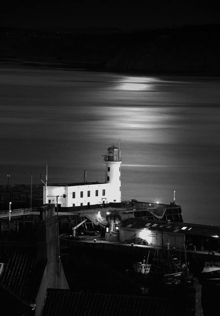A black and white photo of a lighthouse at night.