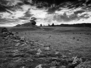 A black and white photo of a stone field with a cloudy sky.