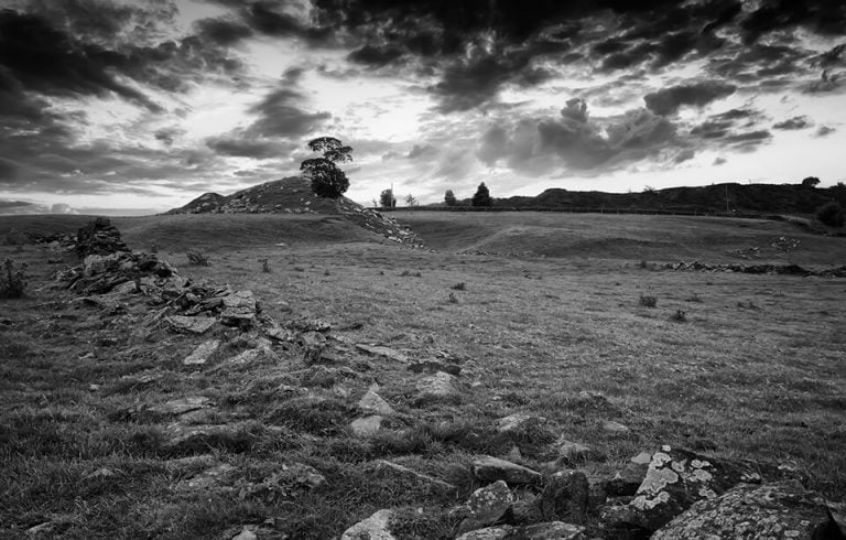 A black and white photo of a stone field with a cloudy sky.