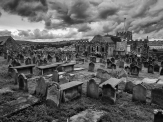 A black and white photo of a cemetery with dark clouds.