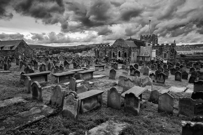 A black and white photo of a cemetery with dark clouds.