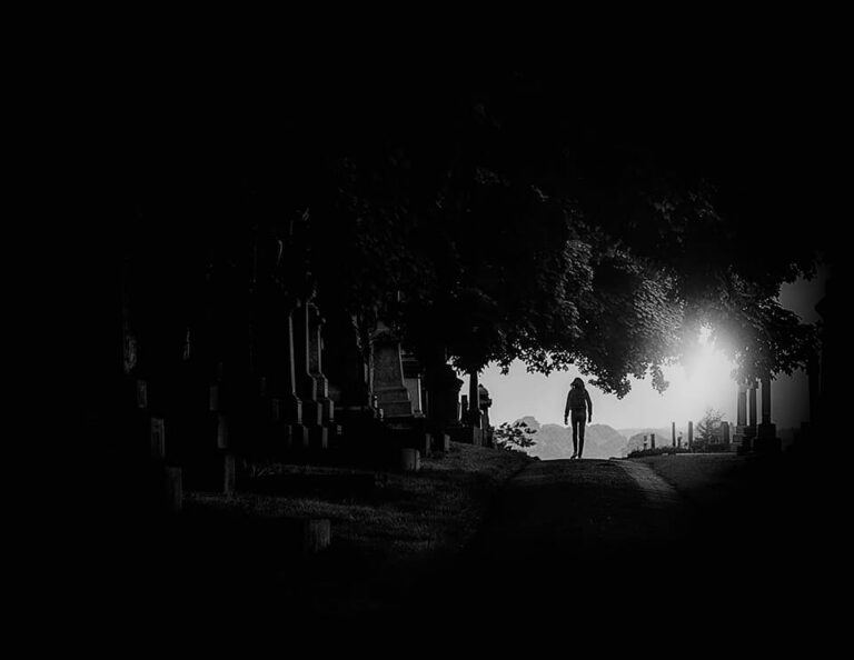 A black and white photo of a person walking in the dark.