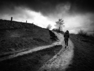 A black and white photo of a person walking down a path.
