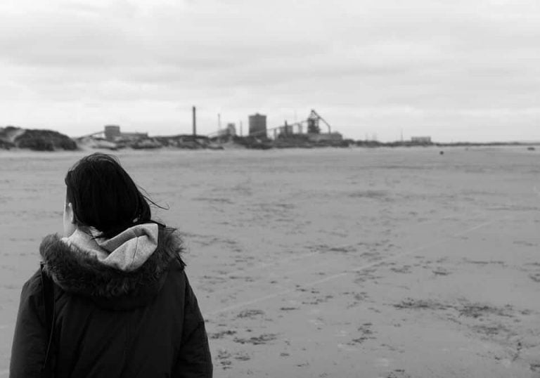Redcar street photograph-16 A black and white photo of a woman walking on the beach.