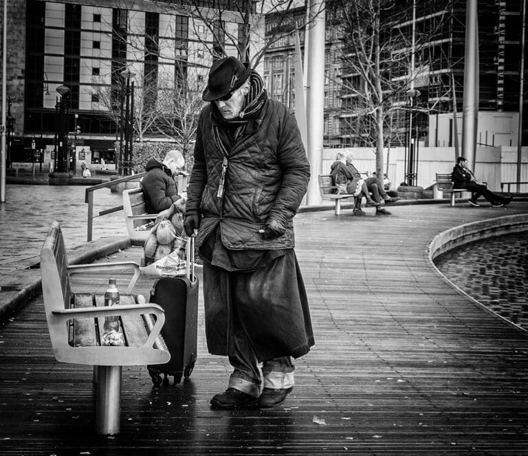 A man with a suitcase on a sidewalk.