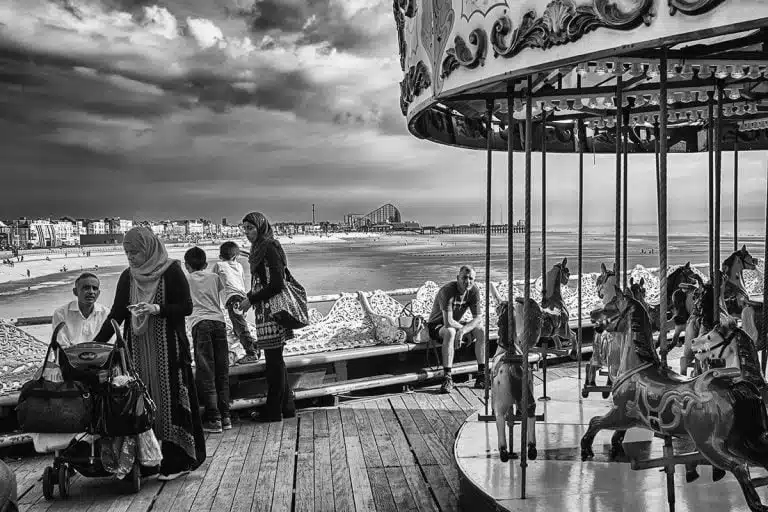A black and white photo of a carousel on the beach.