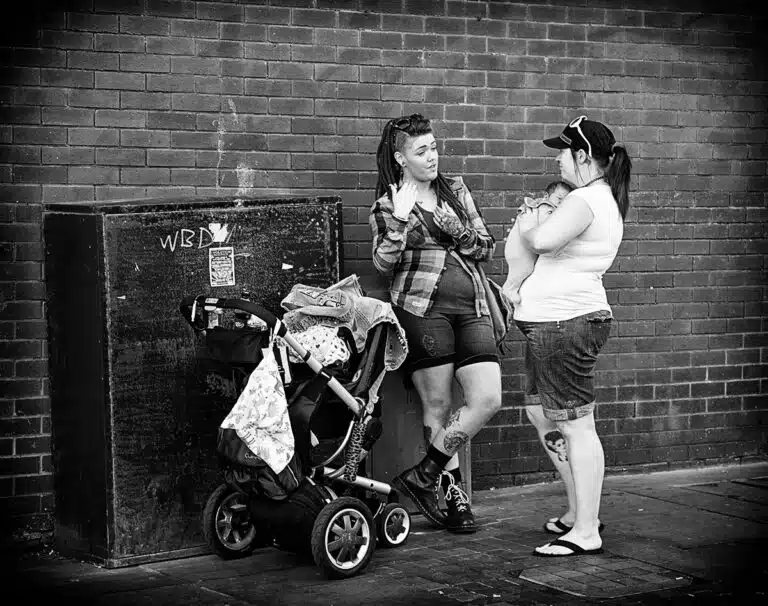 Two women standing next to a baby carriage.