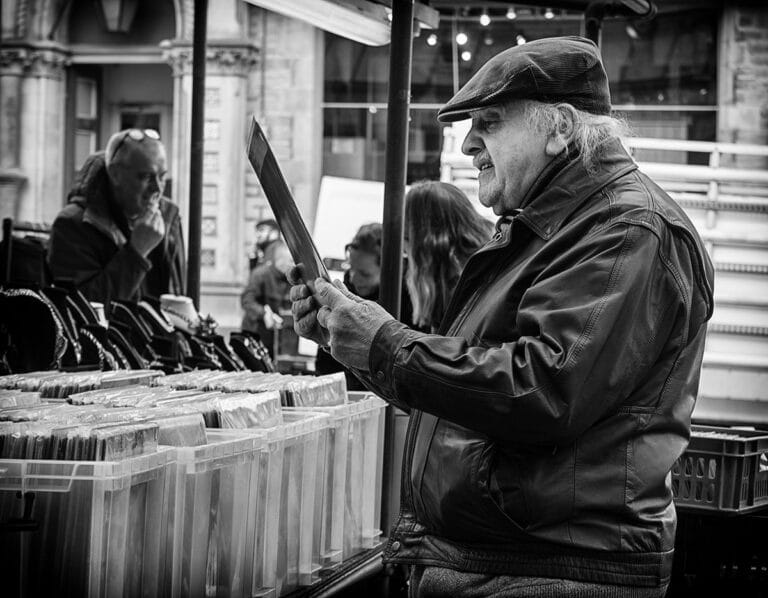 A man is holding a knife at an outdoor market.