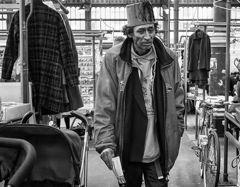 A man in a hat walking through a market.