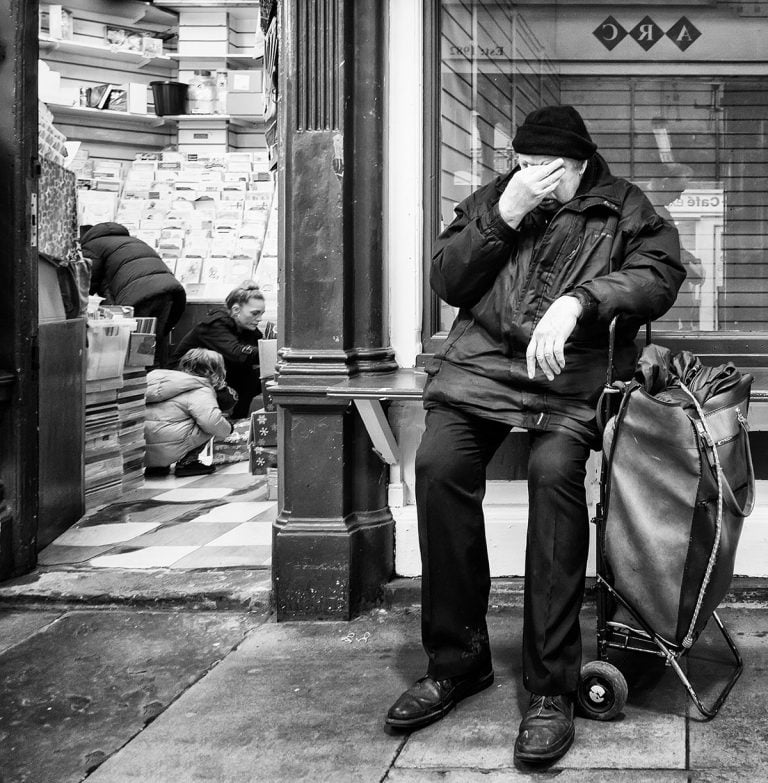 A man sitting on a bench with a suitcase.