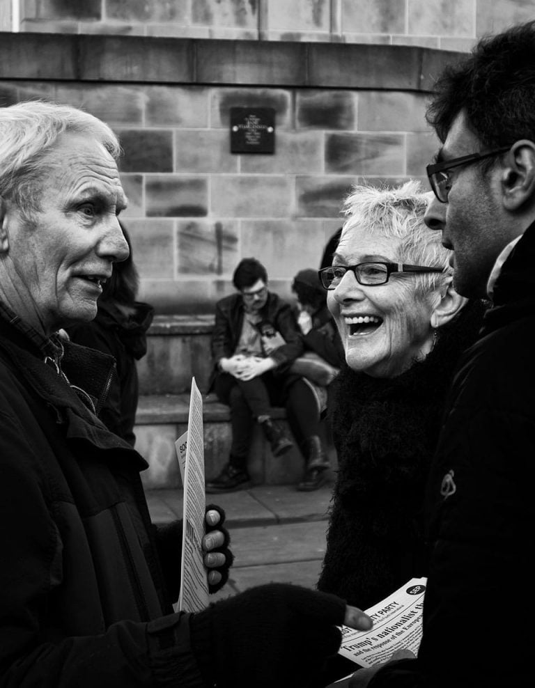Black and white photo of two people talking to each other.