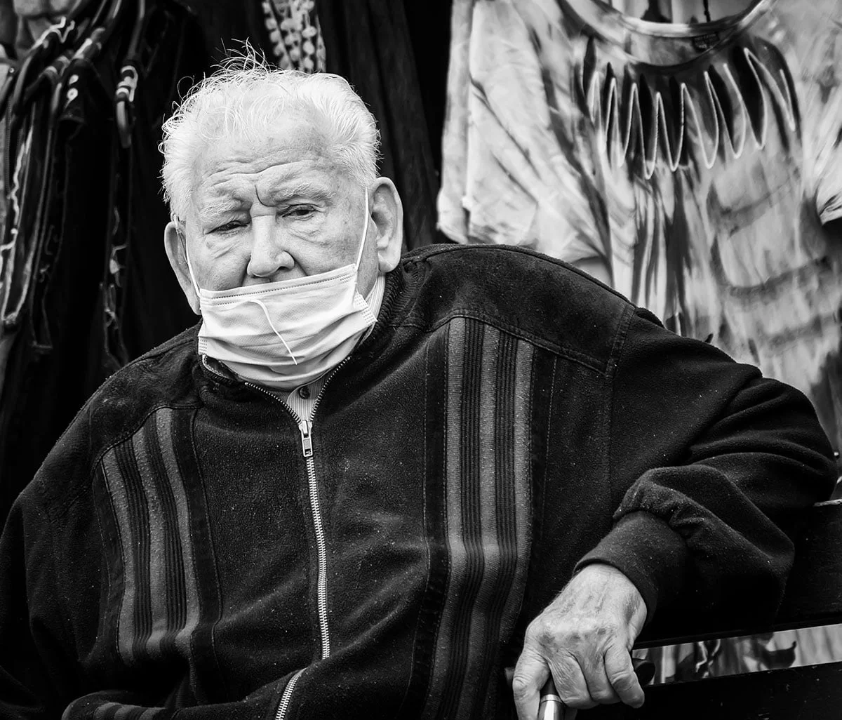 Review of the year 2020 15 A man wearing a face mask sitting on a bench.