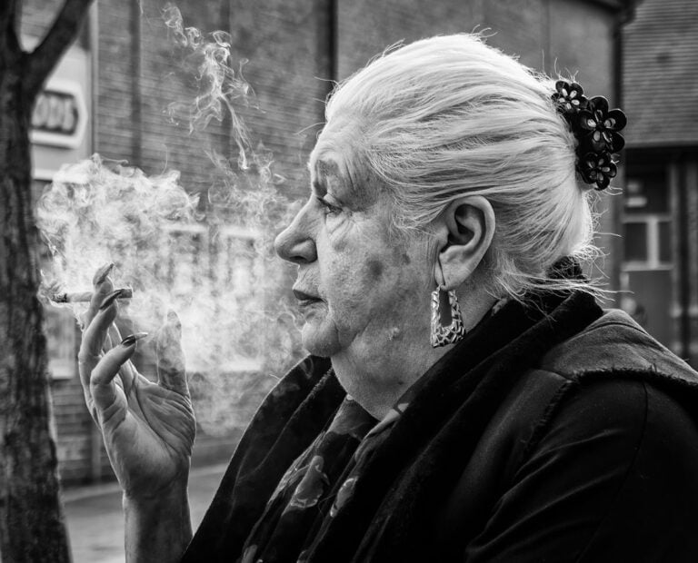 A woman smoking a cigarette in a black and white photo.