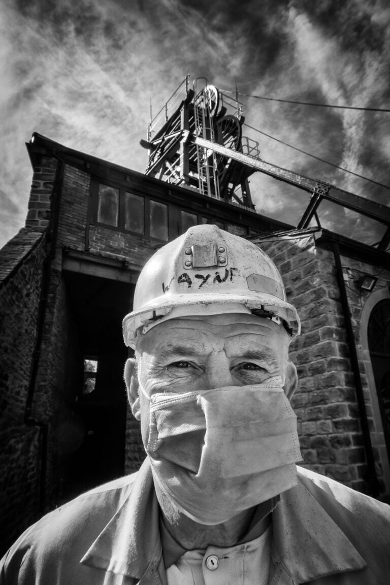 A man wearing a face mask in front of a coal mine.