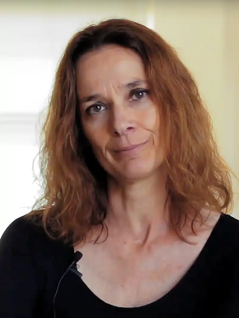 A woman in a black top is looking at the camera.