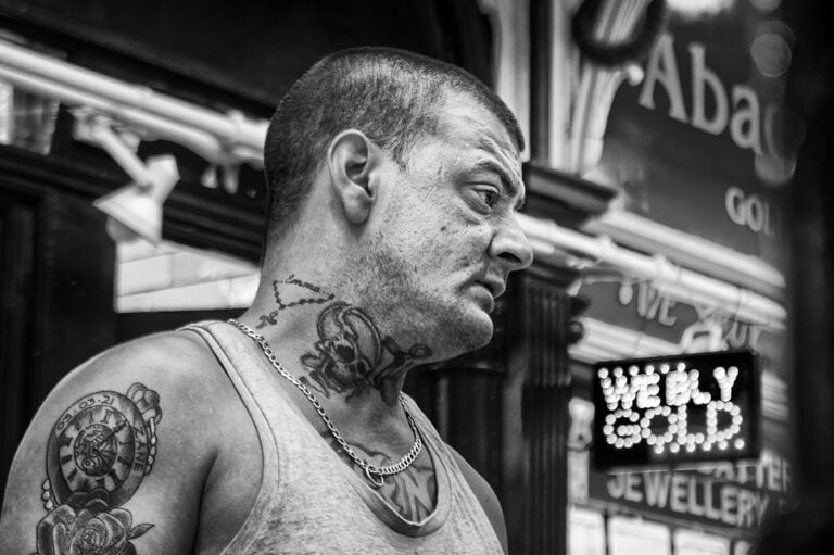 Black and white photo of a man with tattoos.