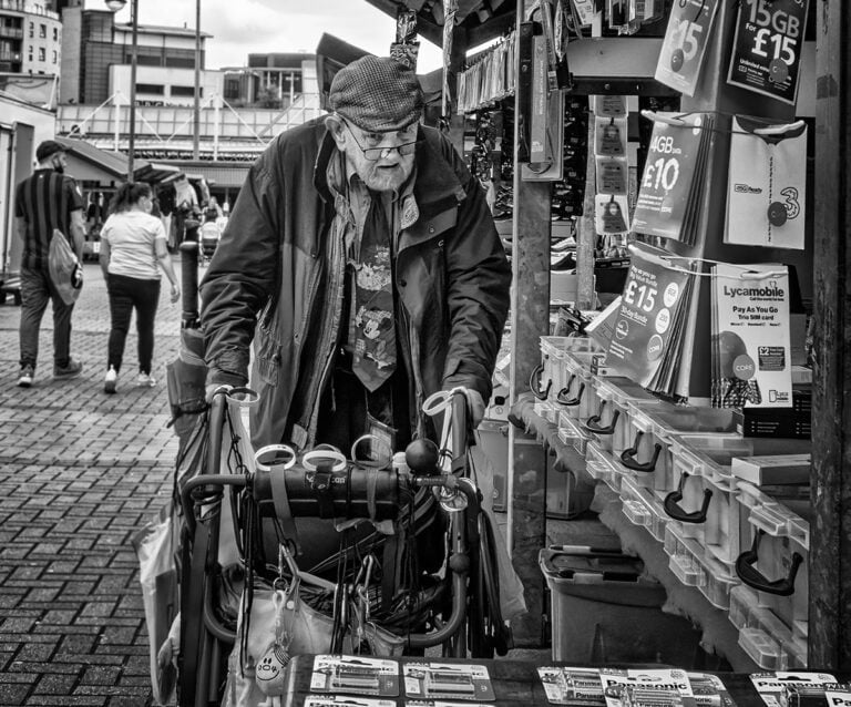 An old man pushing a cart full of books.