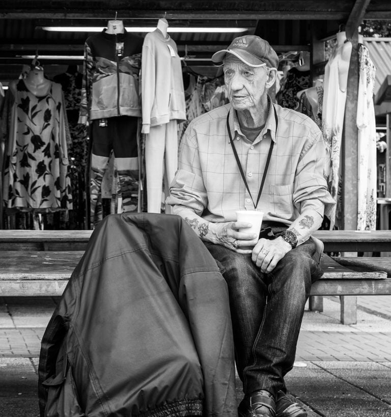 A man sitting on a bench with a cup of coffee.