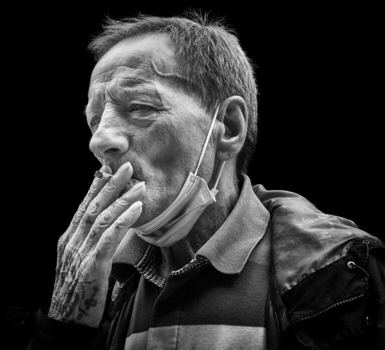 A black and white photo of a man smoking a cigarette.