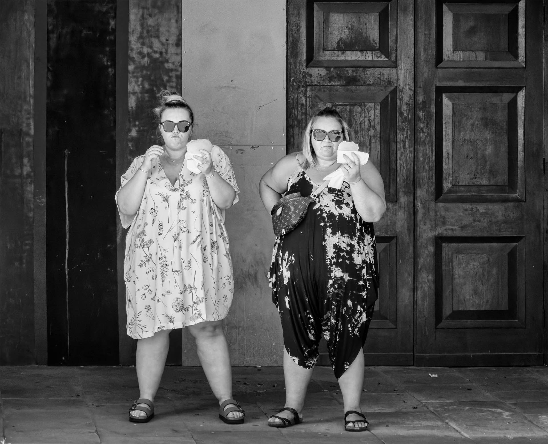 two women in sunglasses eating burgers