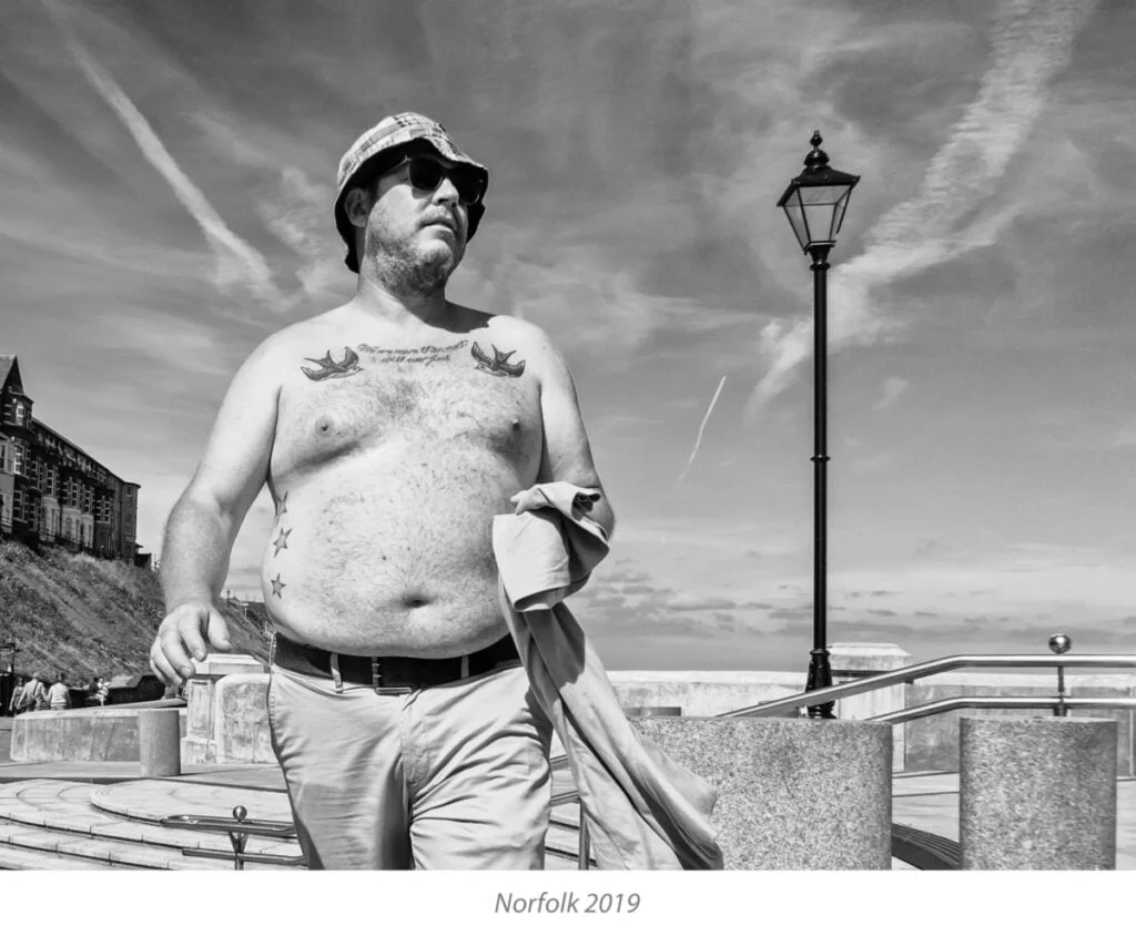 Black and white photo of a man with a tattoo on his chest.